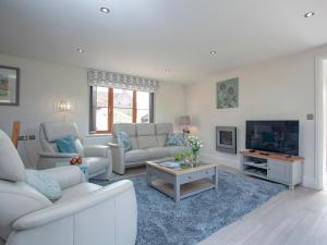 sala de estar con muebles blancos y TV en The Linhay, en Durleigh