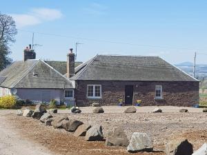a stone house with rocks in front of it at Baldowrie Farm Cottage in Ardler