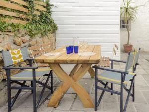 a wooden table and chairs with blue glasses on it at Churchtown Cottage in Cubert