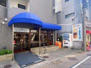 un paraguas azul frente a un edificio en E Hotel Warabi, en Warabi
