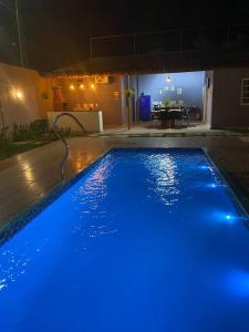 瓜拉帕里的住宿－Casa_praia_Laphina - Frente do mar com piscina!，夜间在院子里设有蓝色灯光的游泳池