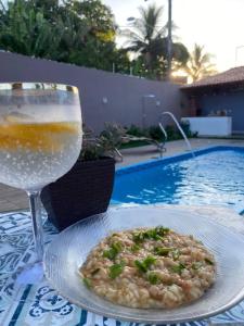 una bebida y un plato de comida en una mesa cerca de una piscina en Casa_praia_Laphina - Frente do mar com piscina! en Guarapari