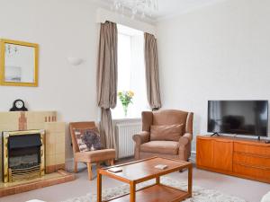 a living room with a tv and a couch and chairs at Moray Cottage in Wick