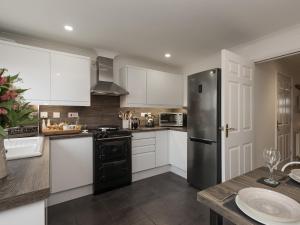 a kitchen with white cabinets and a black refrigerator at River Quay in Gorleston-on-Sea