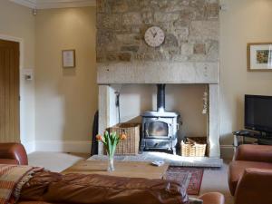 a living room with a stone fireplace with a wood stove at Wagtail Cottage in Lesbury