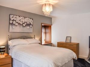 a bedroom with a white bed and a chandelier at Belger Cottage in Inverallochy