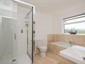 a bathroom with a tub and a toilet and a sink at Crinkum in Titchwell