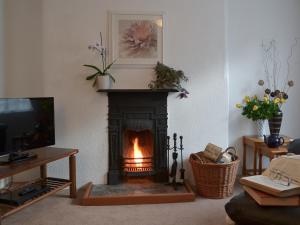 a living room with a fireplace and a tv at Bridgend Cottage in Lostwithiel