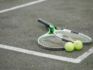 two tennis rackets and two tennis balls on a court at The Hay Barn in Sidbury