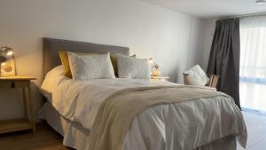 a bedroom with a bed with white sheets and a window at Calma Home in Buenos Aires