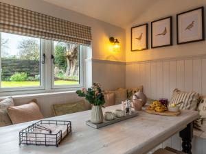 a dining room with a table and two windows at Church Cottage in Thurlton