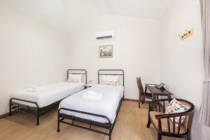 two beds in a room with a desk and a chair at Picha Ville Resort in Watthana Nakhon