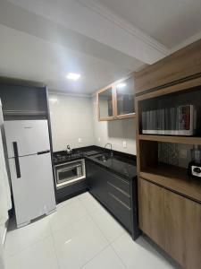 eine kleine Küche mit Kühlschrank und Spüle in der Unterkunft RECANTO RESIDENCIAL MARISCAL APT03 in Bombinhas