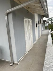 ein weißes Gebäude mit einer Tür und einem Gehweg in der Unterkunft RECANTO RESIDENCIAL MARISCAL APT03 in Bombinhas