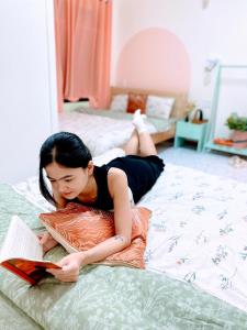 a woman laying on a bed reading a book at Wasabi House 2 gần chợ đêm 5p đi bộ in Da Lat