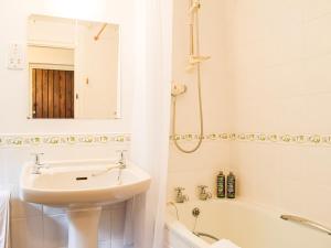a white bathroom with a sink and a bath tub at The Hill Cottage Apartment in Wollaston
