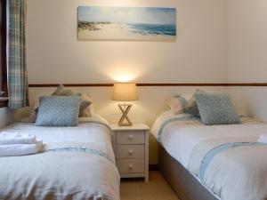 a bedroom with two beds and a lamp on a night stand at Cotton Shore in Inverallochy