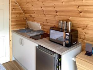 een kleine keuken met een magnetron en een wastafel bij The Dalmore Pod in Alness