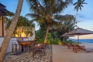 um restaurante na praia com mesas e cadeiras em Three Gables Boutique Villa em Mirissa