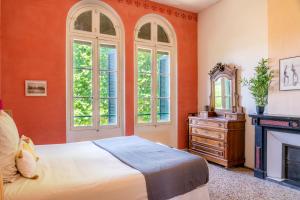 ペズナにあるUltimate Relaxation for Family or Group at Renowned Couvent des Ursulines, a Tranquil Escape in Historic Pézenasのオレンジ色の壁のベッドルーム(ベッド1台、暖炉付)