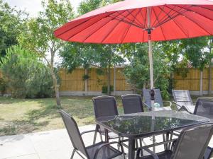 a table with a red umbrella on a patio at 185 Golf Road in Mablethorpe