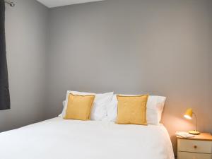 a bedroom with a white bed with yellow pillows at Hare Lodge - Uk30604 in Pidley
