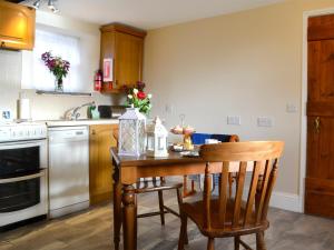 uma cozinha com uma mesa de madeira com cadeiras e um fogão em Buckswell Cottage em Hury