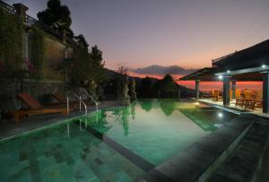 a large swimming pool with a sunset in the background at Rostika Hotel & Camping Sekumpul in Buleleng