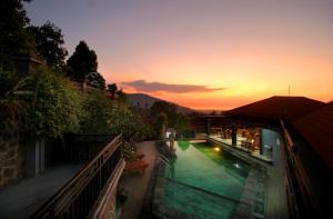 een gebouw met een zwembad met een zonsondergang op de achtergrond bij Rostika Hotel & Camping Sekumpul in Buleleng