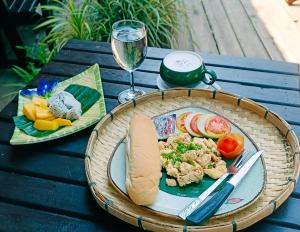 a table with a plate of food and a glass of wine at Ou River House in Nongkhiaw
