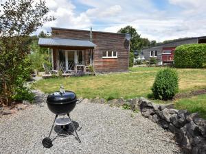 a bbq grill in a yard with a house at Detached holiday home in the Vulkaneifel in Berlingen