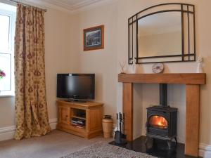 a living room with a fireplace and a television at Rowan House in Threlkeld