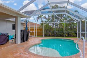 - une piscine avec une grande maison en verre dotée d'une terrasse dans l'établissement Beautiful Pool Home with Sleeping for 8 for LovelyPeople, à Cape Coral