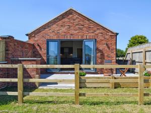 a brick house with a wooden fence in front of it at Harrys Den in Chapel Saint Leonards