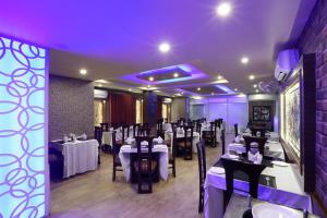 uma sala de jantar com mesas e cadeiras e iluminação roxa em Hotel Blue Bird, Nagaon em Nowgong