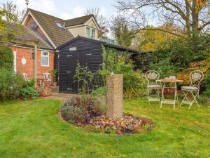 Burgh的住宿－Garden Cottage，一个带桌椅的花园以及一座房子