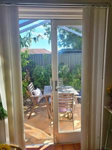 Une porte ouverte s'ouvre sur une terrasse avec une table et des chaises. dans l'établissement 11 chartwell, à Brisbane