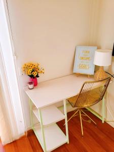un escritorio blanco con una lámpara y un jarrón de flores en 11 chartwell en Brisbane