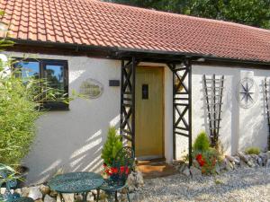 a small white cottage with a yellow door and a table at Lambs Cottage in Culmstock