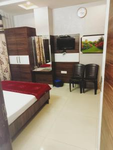 a bedroom with a bed and a tv and chairs at Hotel Robin Inn in Amritsar +16 photos