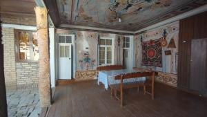 Habitación con mesa y techo con pinturas. en Reyhana Unique House, en Samarkand