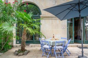 een blauwe tafel met stoelen en een parasol bij Ultimate Relaxation for Family or Group at Renowned Couvent des Ursulines, a Tranquil Escape in Historic Pézenas in Pézenas