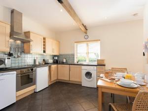 a kitchen with white appliances and a wooden table at Graham Cottage in Thurning