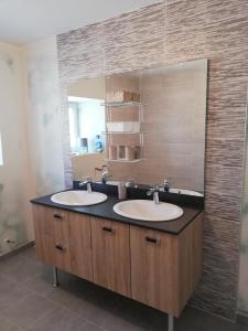 a bathroom with two sinks and a mirror at Gîte du capitaine in Maranville