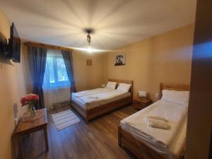 1 dormitorio con 2 camas y una mesa con flores en Pensiunea transilvania, en Covasna