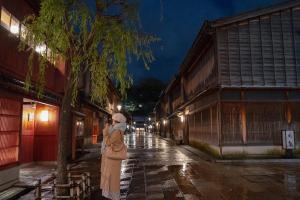 a woman standing on a street at night at 古都とき Kototoki in Kanazawa