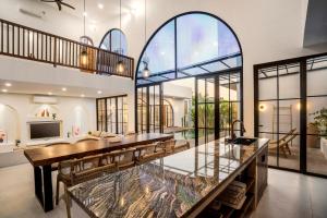 une grande salle à manger avec une grande table et des fenêtres en verre dans l'établissement Casa Copper by Alfred in Bali, à Canggu