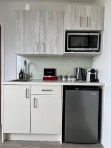 uma cozinha com armários brancos, um micro-ondas e uma máquina de lavar louça em Views on Florence em Queenstown