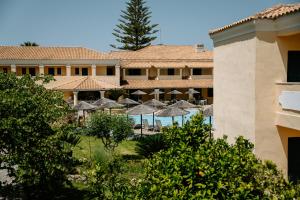 a resort with a pool and umbrellas and a building at Karavostasi Beach Hotel in Perdika