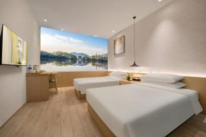 a hotel room with two beds and a view of a lake at Quantum Inn - Hangzhou East Railway Station in Hangzhou